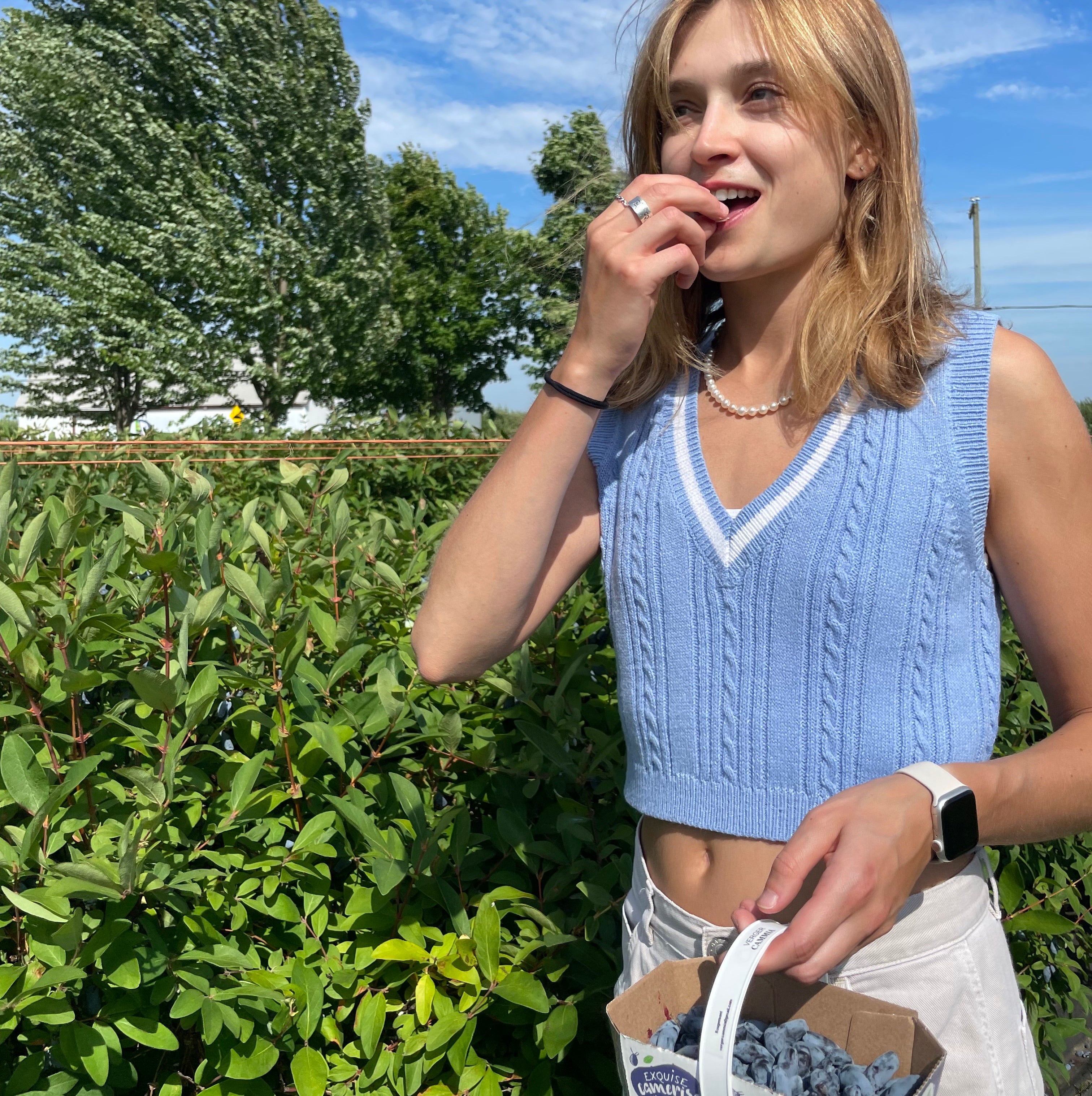 photo d'une jeune femme mangeant une camerise, ingredient principal de la gamme lèvres Nurish, dans la cameriseraie Verger de Cammia
