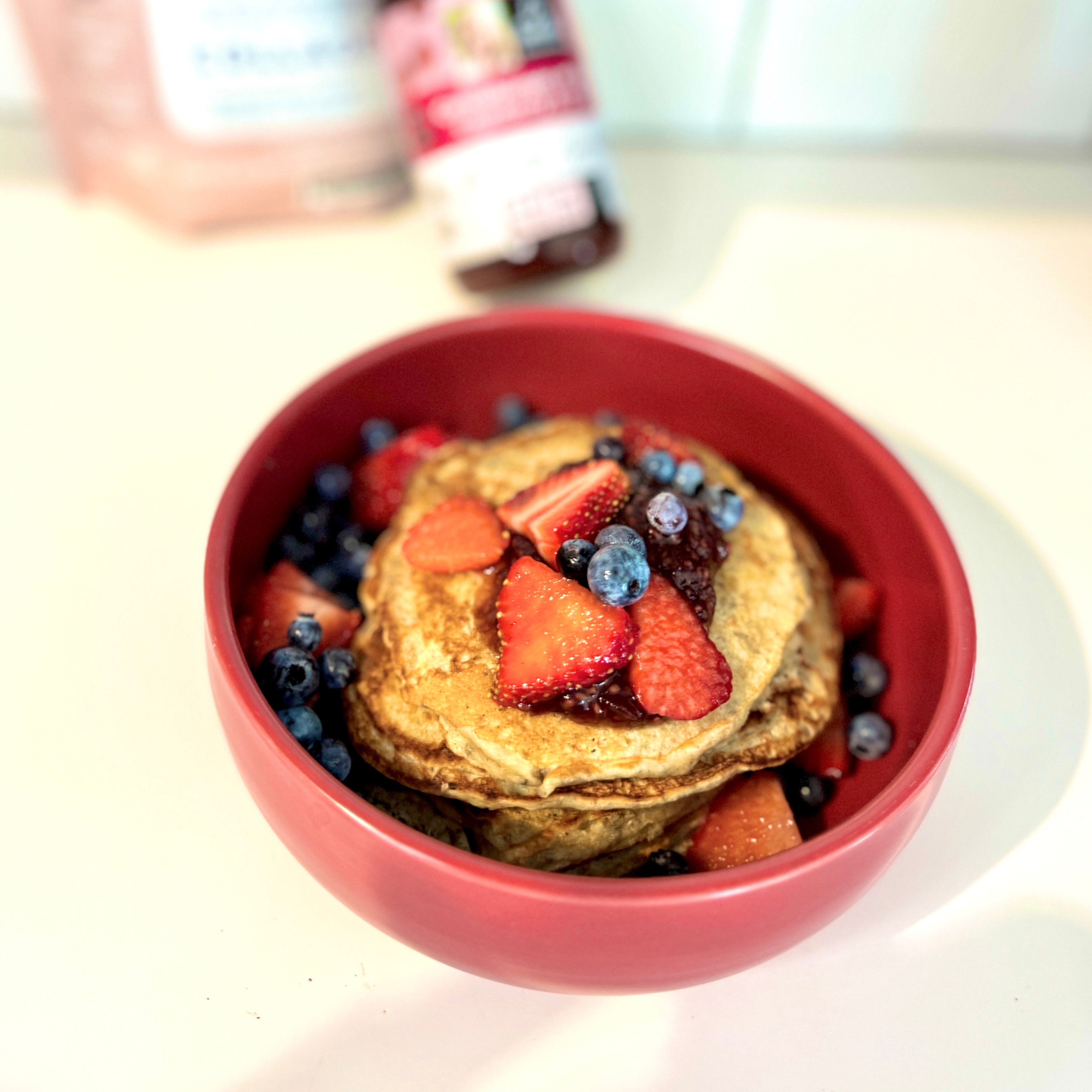 Pancakes santé garnis de fraises et de bleuets pour le déjeuner. Healthy pancakes topped with strawberries and blueberries for breakfast.