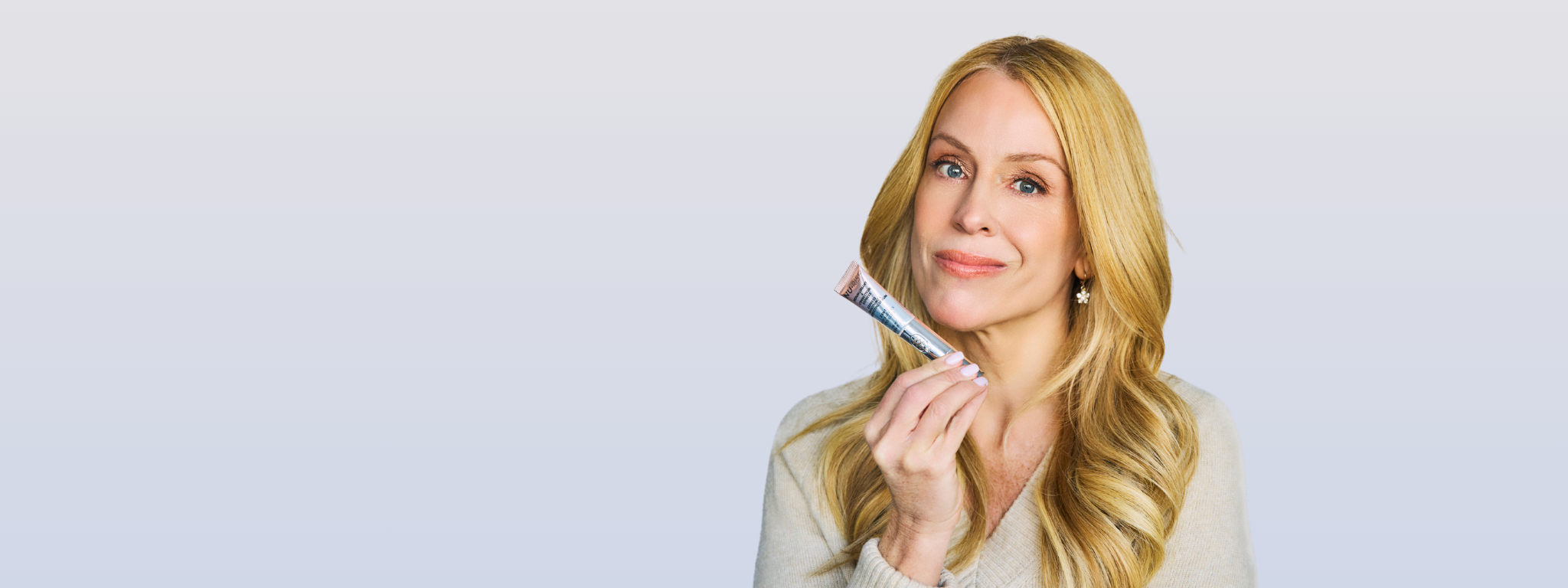 Isabelle Huot avec son sérum express 2-en1 yeux et lèvres, sur un fond bleu très clair.