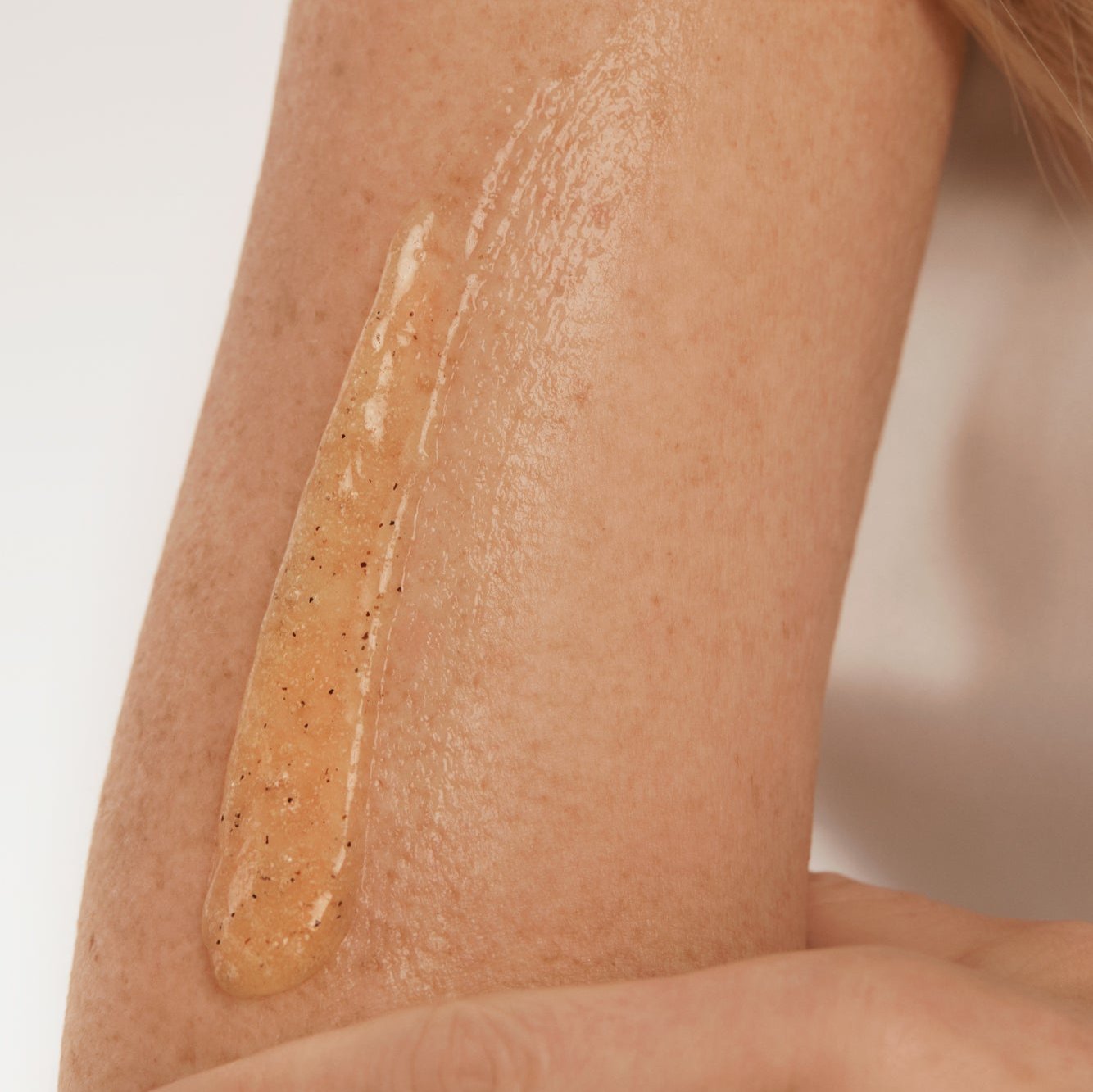 Application d’un gel exfoliant corporel NU•RISH sur la peau, texture naturelle avec grains exfoliants pour lisser et revitaliser l’épiderme. Application of NU•RISH body exfoliating gel to the skin, natural texture with exfoliating grains to smooth and revitalize the epidermis.