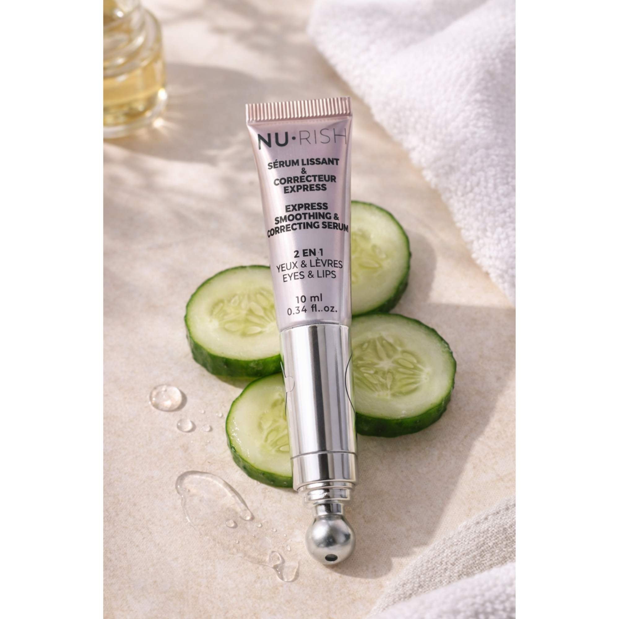 Sérum lissant et correcteur express 2-en-1 NU•RISH pour les yeux et les lèvres, présenté avec des tranches de concombre sur fond clair. NU•RISH 2-in-1 express smoothing and correcting serum for eyes and lips, presented with cucumber slices on a light background.