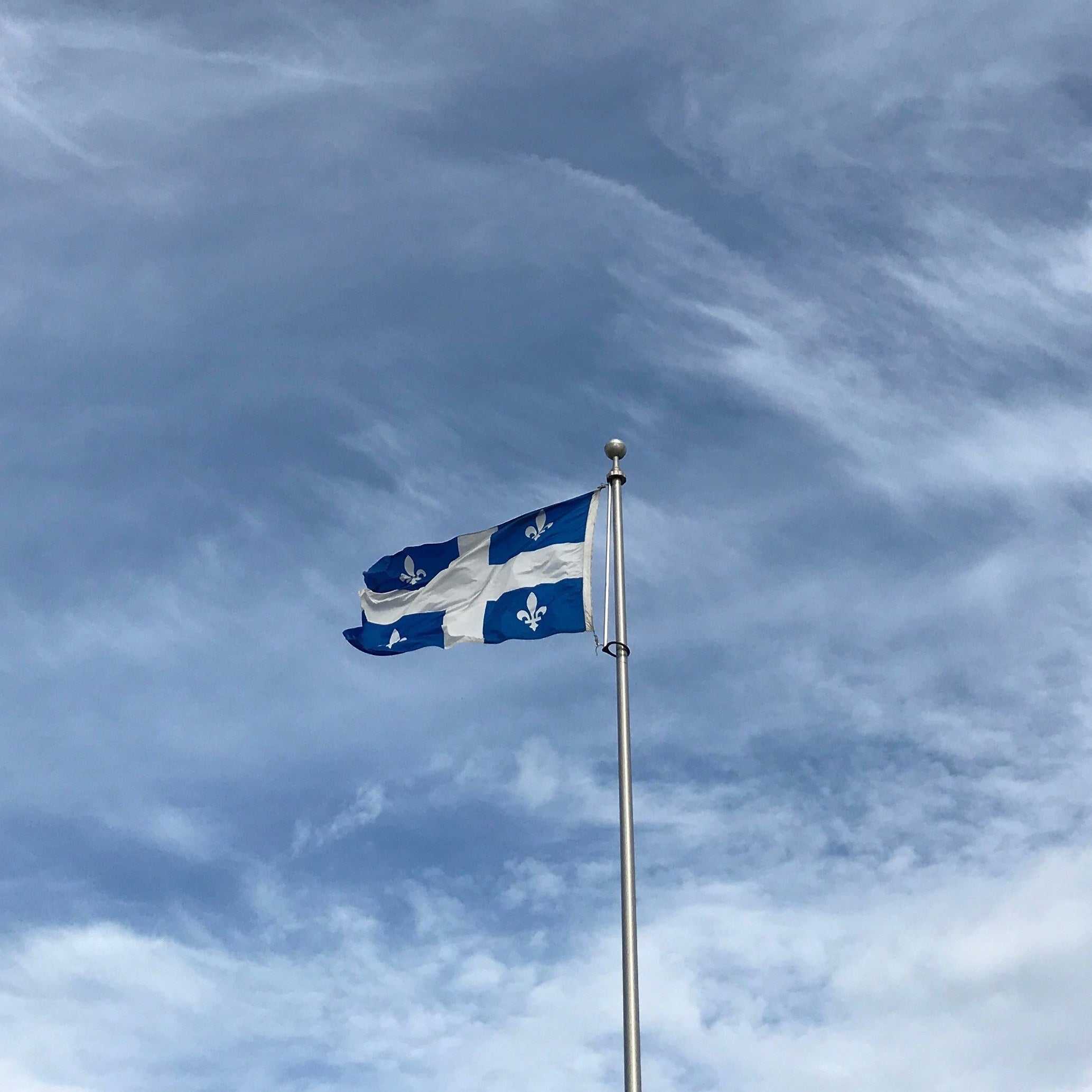 Drapeau du Québec avec un ciel bleu en fond.